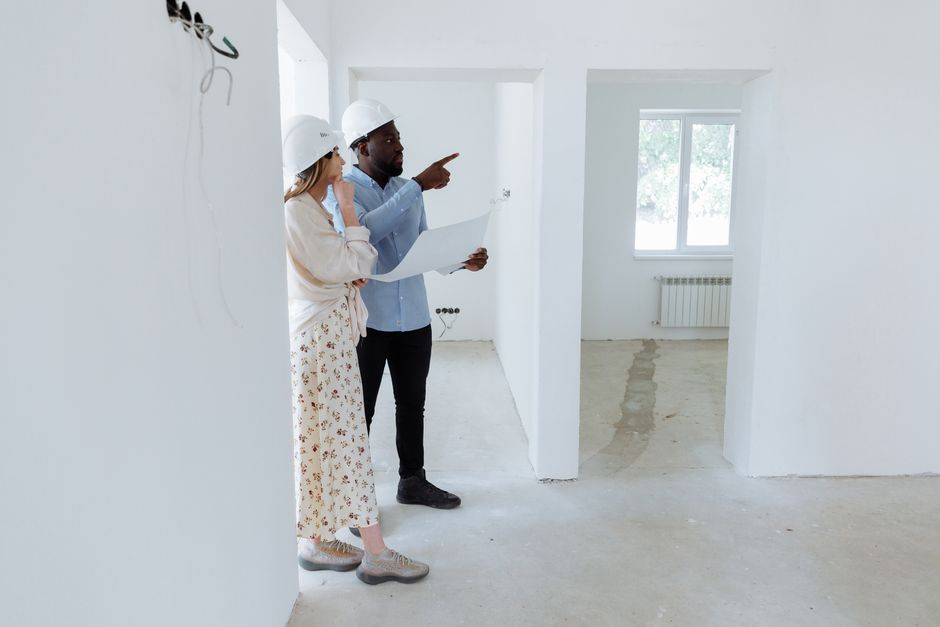 Architects in hard hats discussing plans inside an unfinished building.