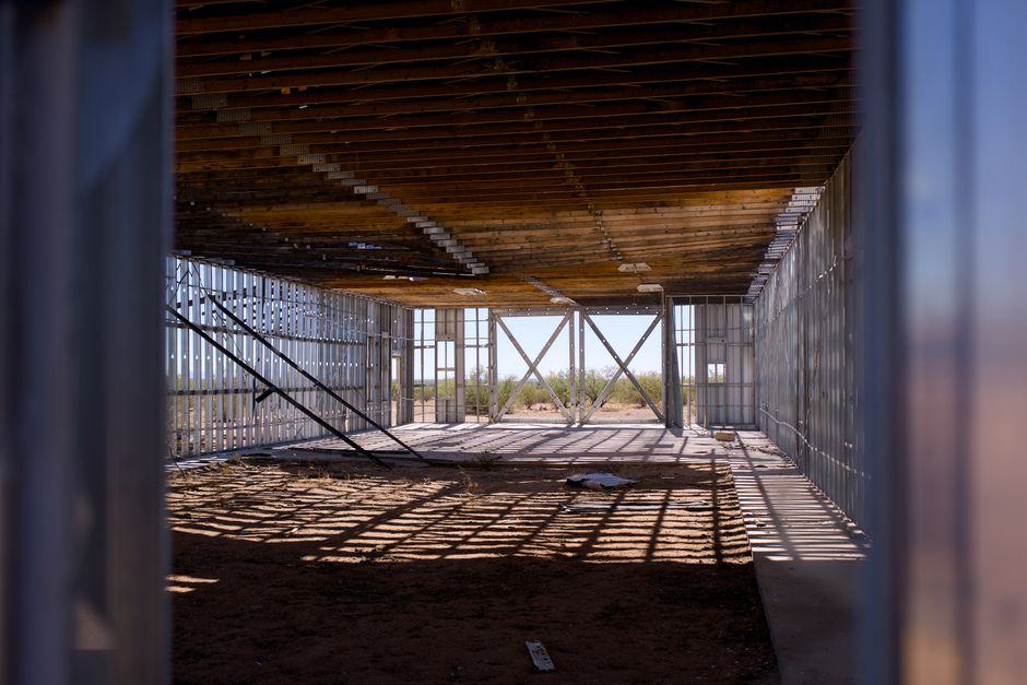 Interior view of a construction site with metal framing and wooden ceiling, under bright sunlight.
